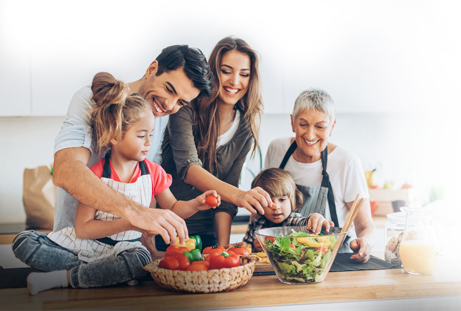 Family in a kitchen holding fruits and vegetables